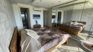 Een moderne slaapkamer met een groot bed, een houten nachtkastje, een dressoir en een spiegel.