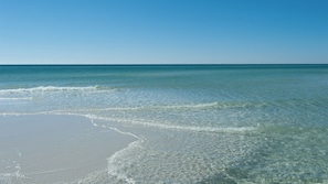 Uma praia com águas claras e rasas e uma faixa de areia.