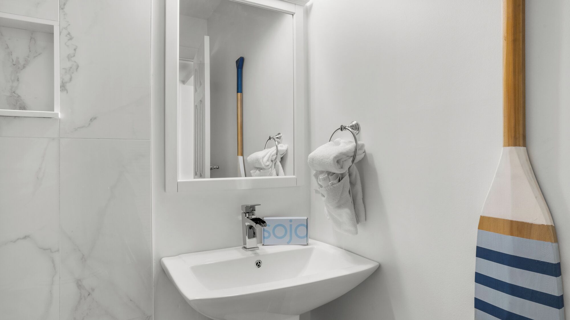 A bathroom with a white sink, a mirror, and a towel rack.