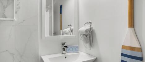 A bathroom with a white sink, a mirror, and a towel rack.