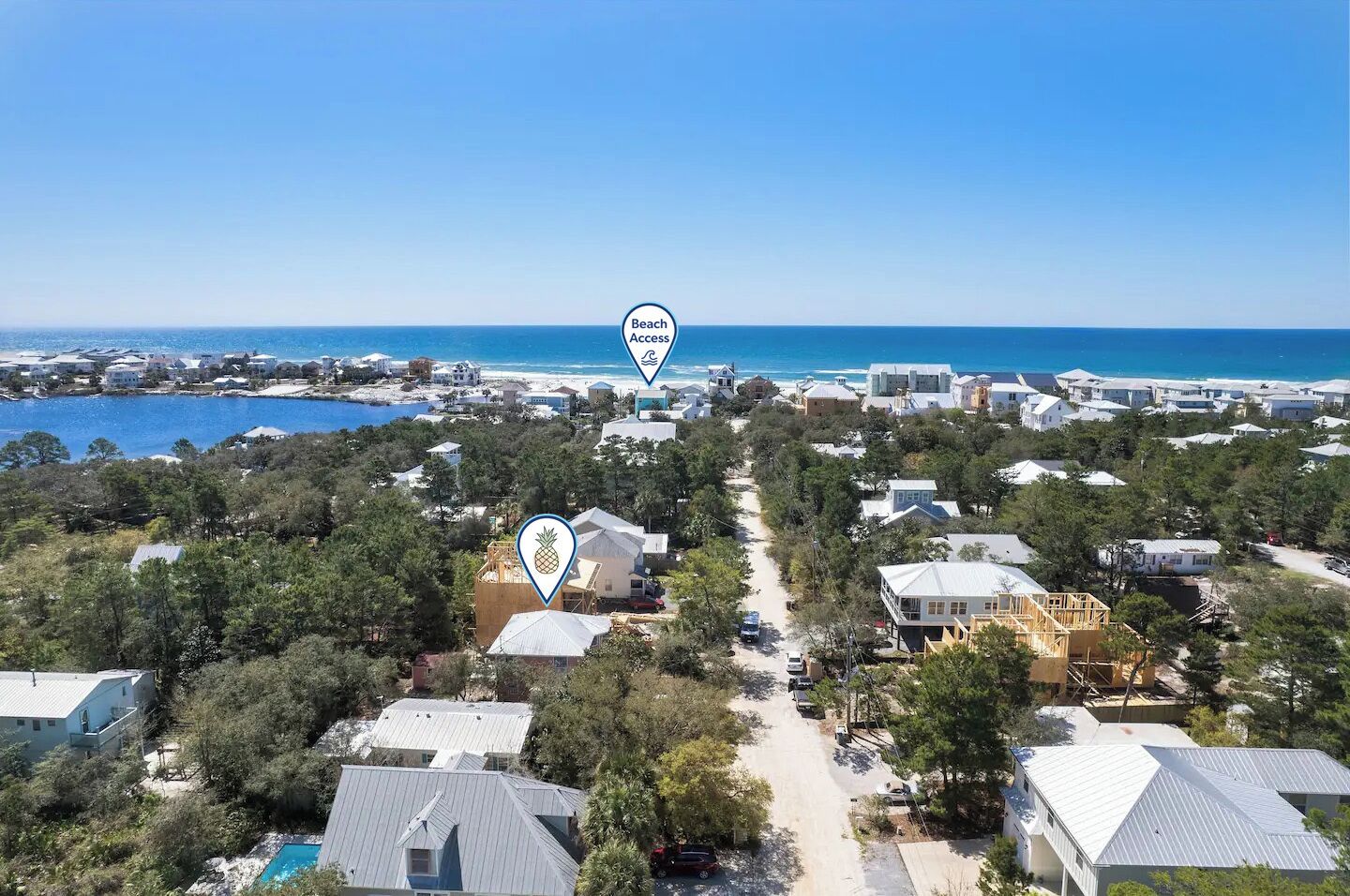 Zona residencial costera con casas, acceso a la playa y una vista despejada del océano.