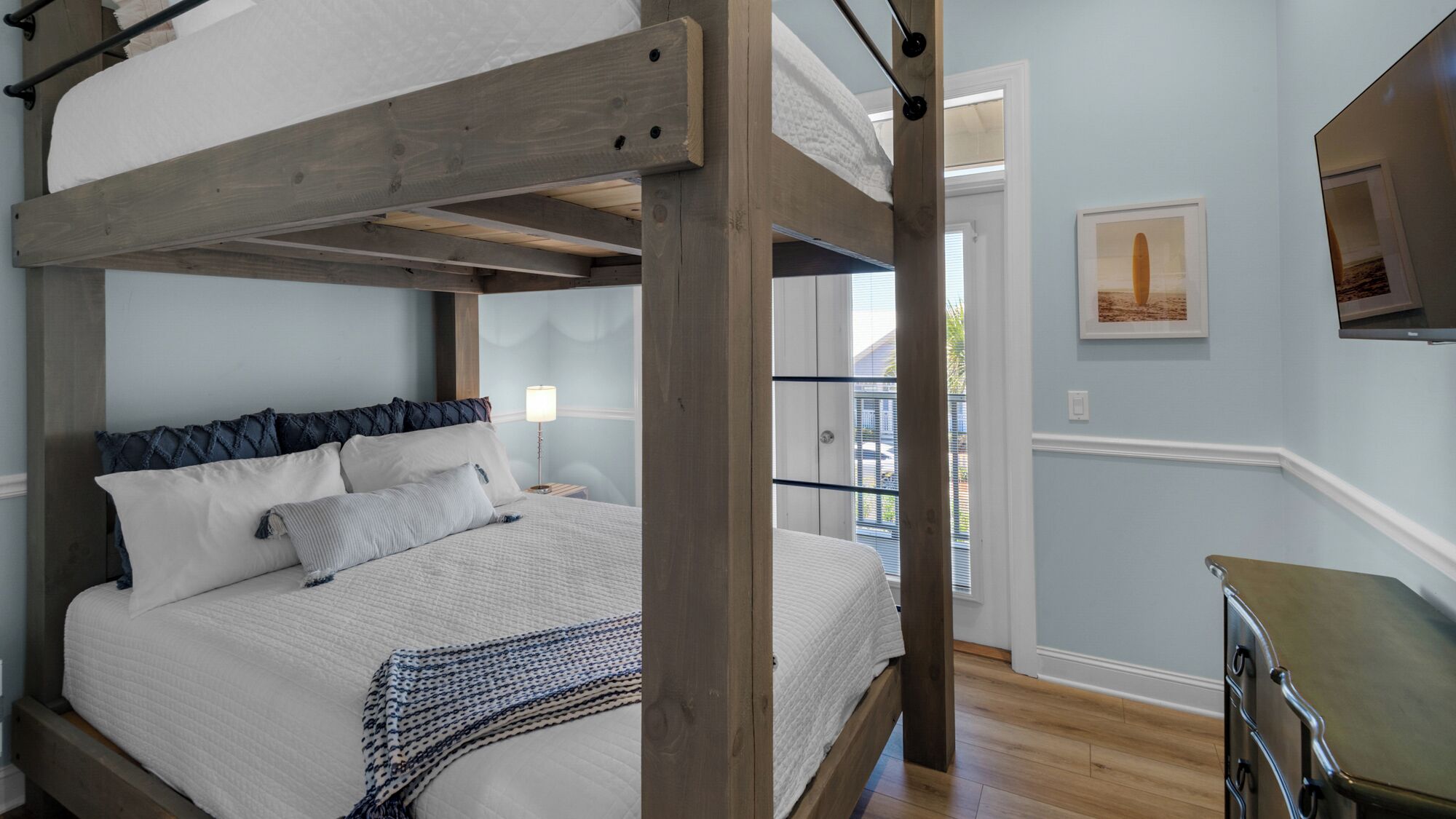 Un letto a castello con struttura in legno, una coperta trapuntata bianca e una coperta decorata con motivi blu e bianchi.