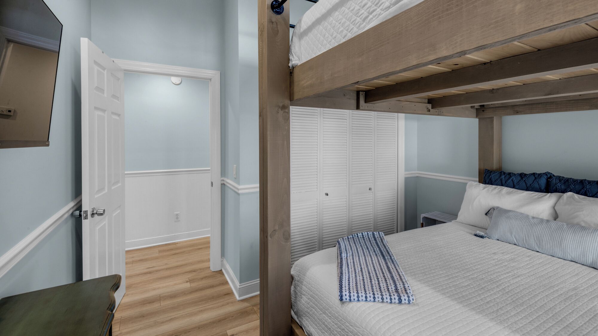 A bedroom with a bunk bed, a wardrobe, and a chair.