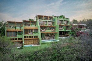 Una casa de varios pisos con fachada verde, balcones de madera y una piscina.