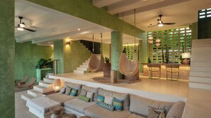 A spacious living area with a large sofa, hanging chairs, and a staircase leading to an upper level. - Punta Nayaá - Adults Only (Santa Maria Colotepec)