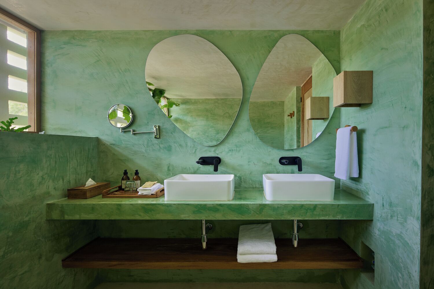 Un baño con dos lavamanos, un espejo y un perchero para toallas.