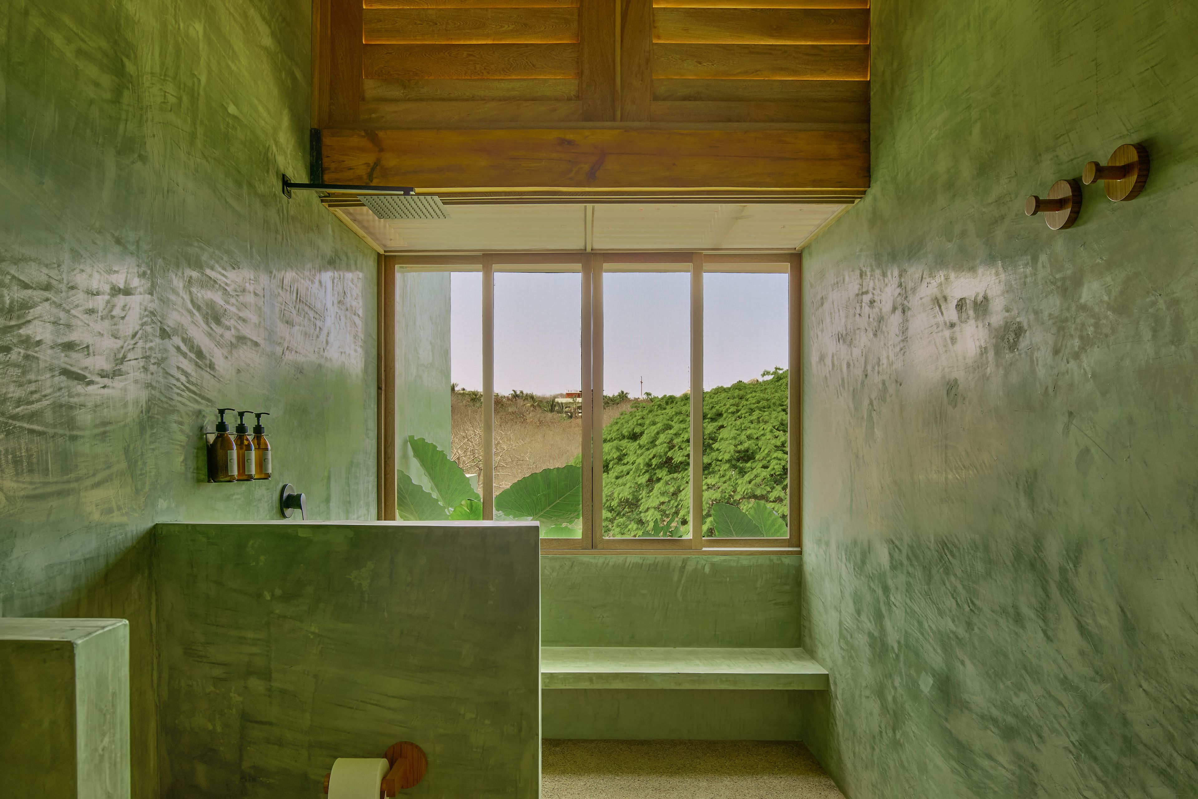 A bathroom with a large window, a wooden ceiling, and a green wall.