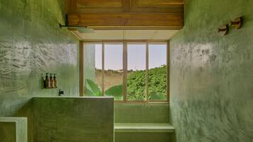 A bathroom with a large window, a wooden ceiling, and a green wall.