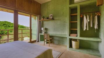 Un dormitorio con una cama grande, una silla, un estante con ropa y vistas al exterior con vegetación.