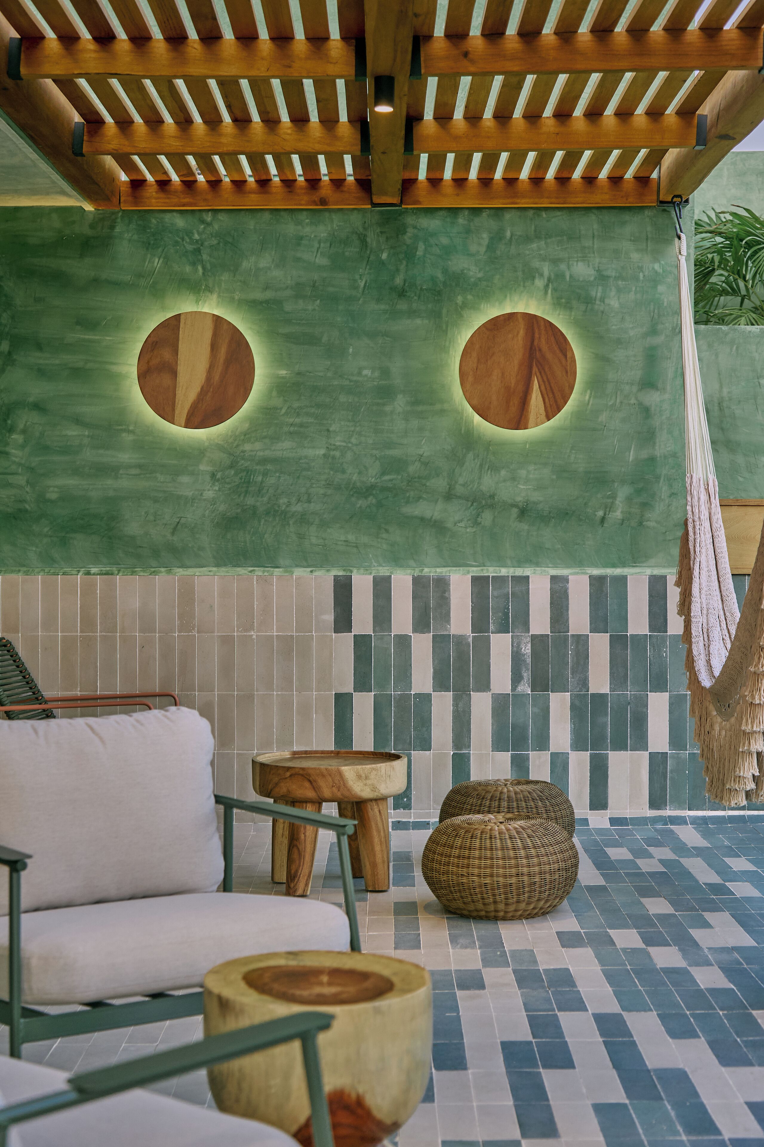 A cozy outdoor seating area with a hammock, a round wooden table, and a cushioned chair.