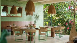 A dining area with wicker chairs and tables, a large mirror, and hanging light fixtures. - Punta Nayaá - Adults Only (Santa Maria Colotepec)