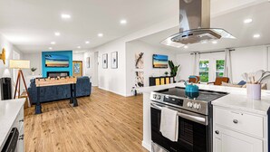 A modern kitchen with a stove, oven, and a blue kettle on the countertop. - Lakefront Modern home. Gorgeous Sunsets! near Sylvan Beach (Canastota)