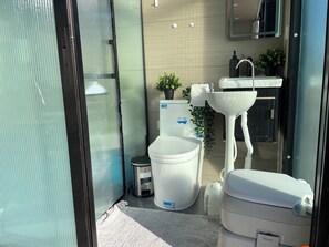 Bathroom features a pedestal sink, toilet, and glass shower enclosure.