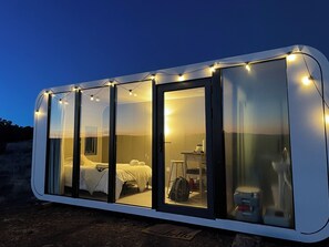 Cozy retreat with a single bedroom, bed, and bedside table, set amidst a natural setting.