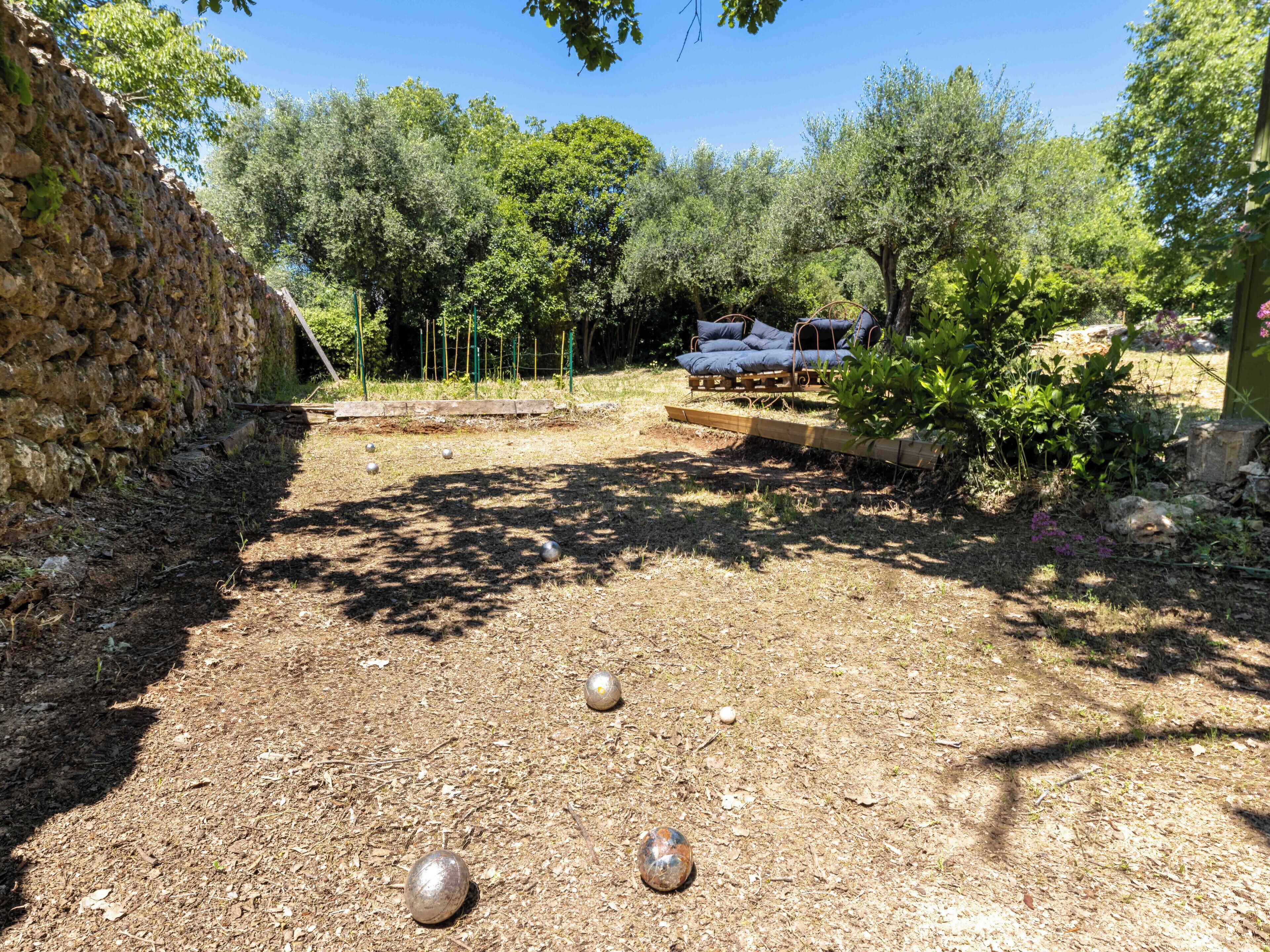 Un cortile con un muro in pietra, una panchina di legno e un pergolato.