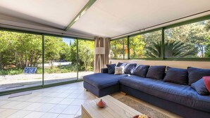 Una sala de estar moderna con un sofá modular, una mesita de centro y vistas a zonas verdes a través de amplios ventanales.