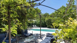 A covered outdoor seating area with a pool in the background. - 06BV2 : Nice cottage with pool (Grasse)