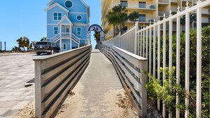 Eine Uferpromenade mit einem blauen Haus, einem weißen Zaun und einem gelben Gebäude im Hintergrund.