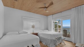 A bedroom with two beds, a ceiling fan, a window with blinds, and a view of the sea through an open door. - 3br/3.ba With Dock, Deck/balcony and Fireplace (Santa Rosa Beach)