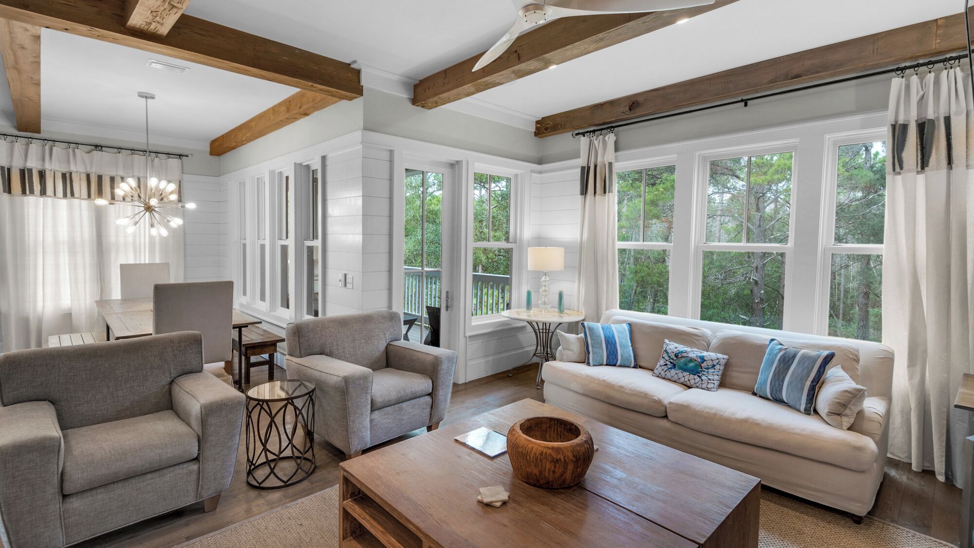 A spacious living room with a large sofa, two armchairs, a coffee table, and a dining area.
