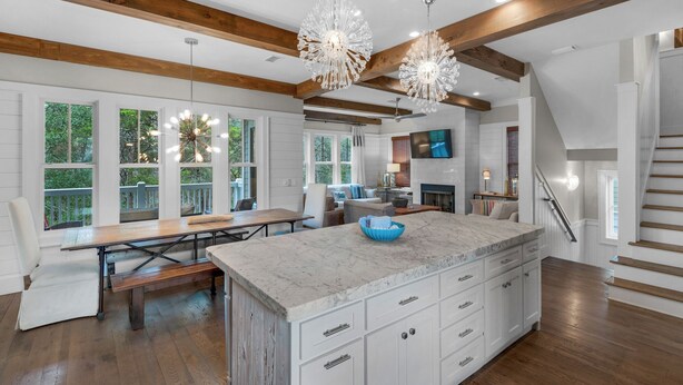 A spacious kitchen with a large island, wooden beams, and a dining area with a bench. - 4 Minutes to Beach + Community Pool ~ Stunning Modern Home for 12 (Santa Rosa Beach)