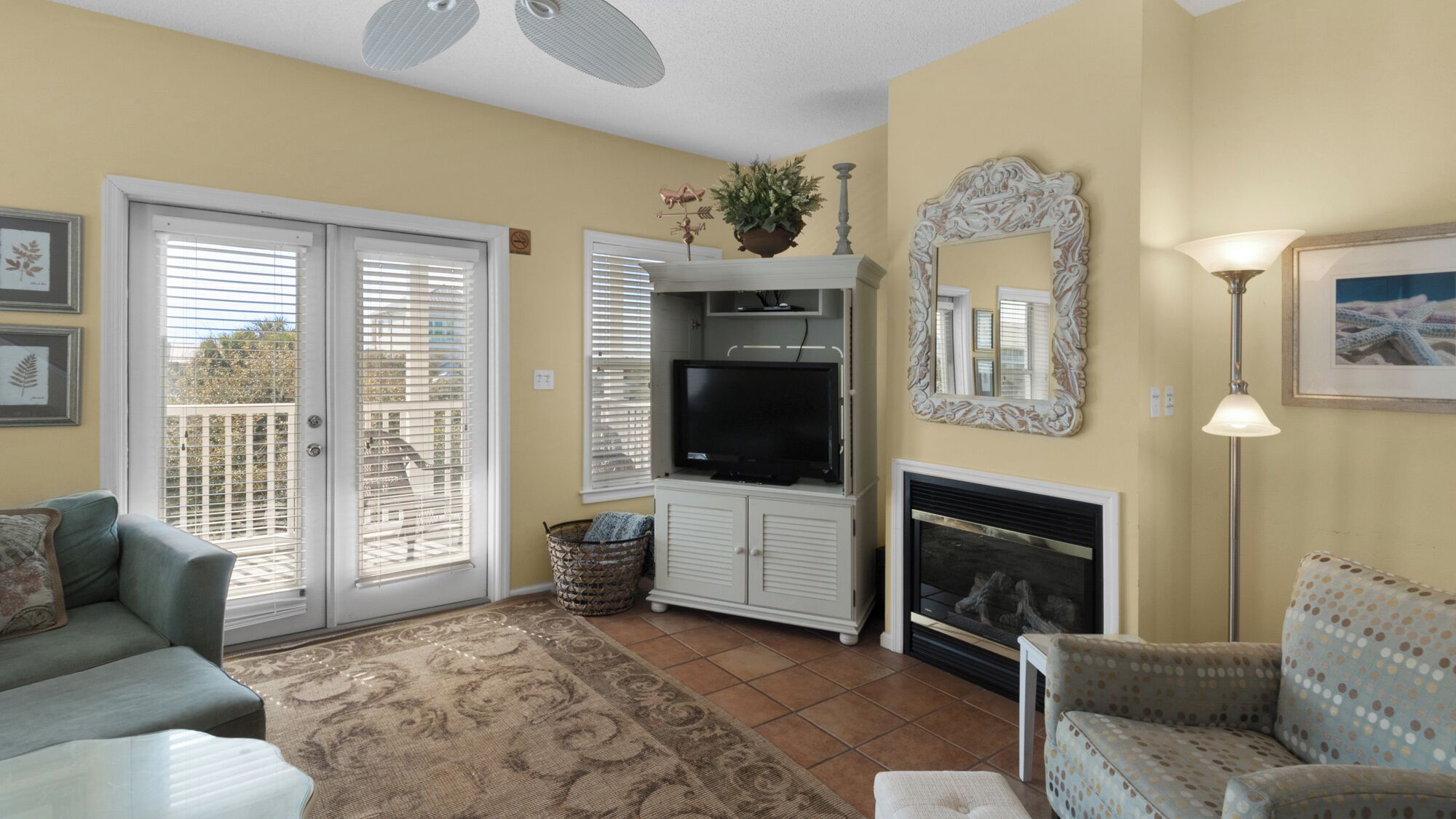 A living room with a fireplace, television, and a balcony with sliding doors.