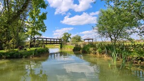 A serene riverside scene with a wooden bridge, a gazebo, and lush greenery. - Captivating 1-bed Cabin in Newmarket (Newmarket)