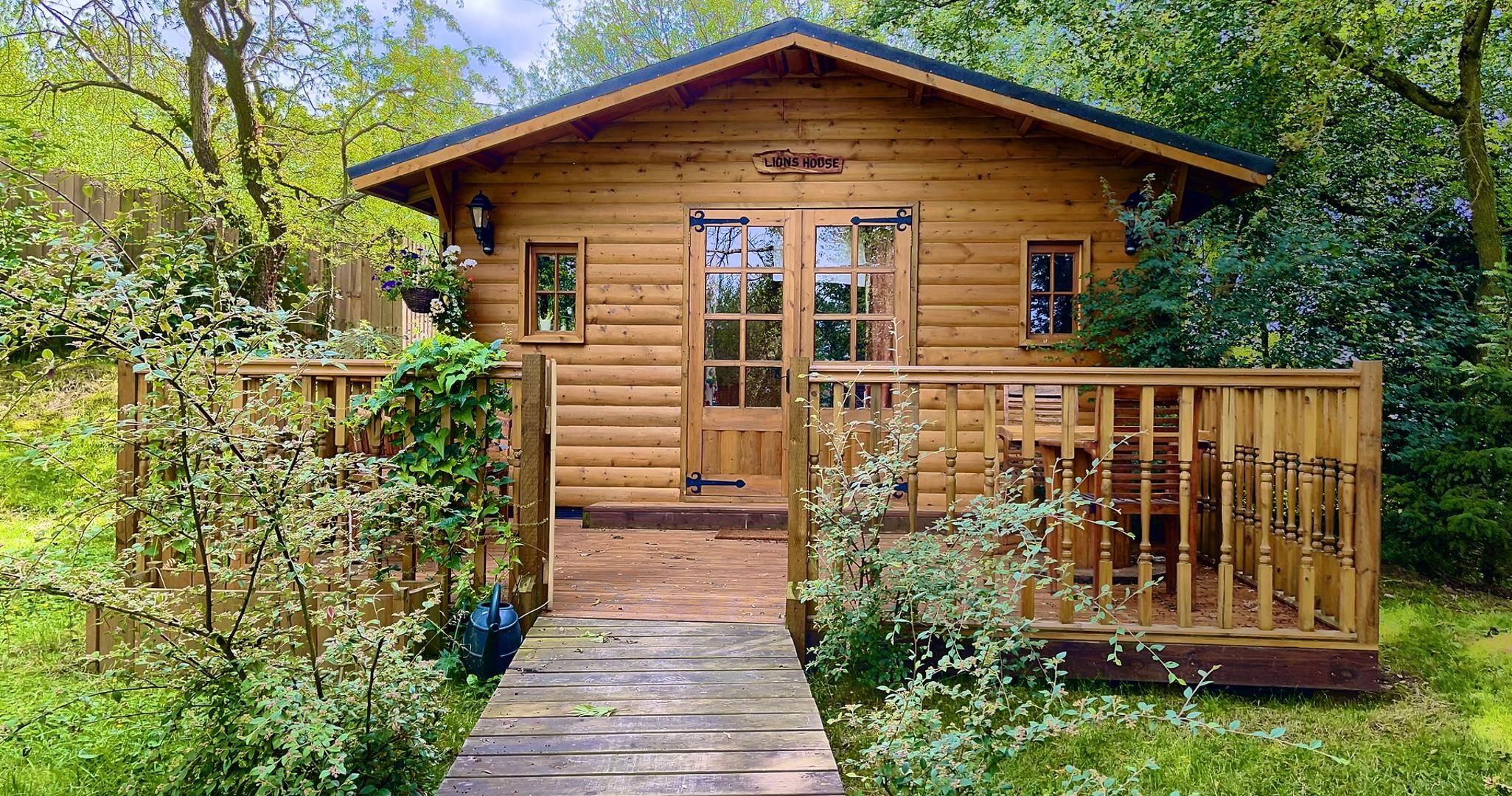 A wooden cabin with a porch and a wooden deck leading to the entrance.
