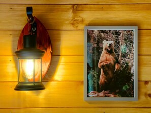 Pared de madera con un farol colgante y un cuadro enmarcado de un oso.