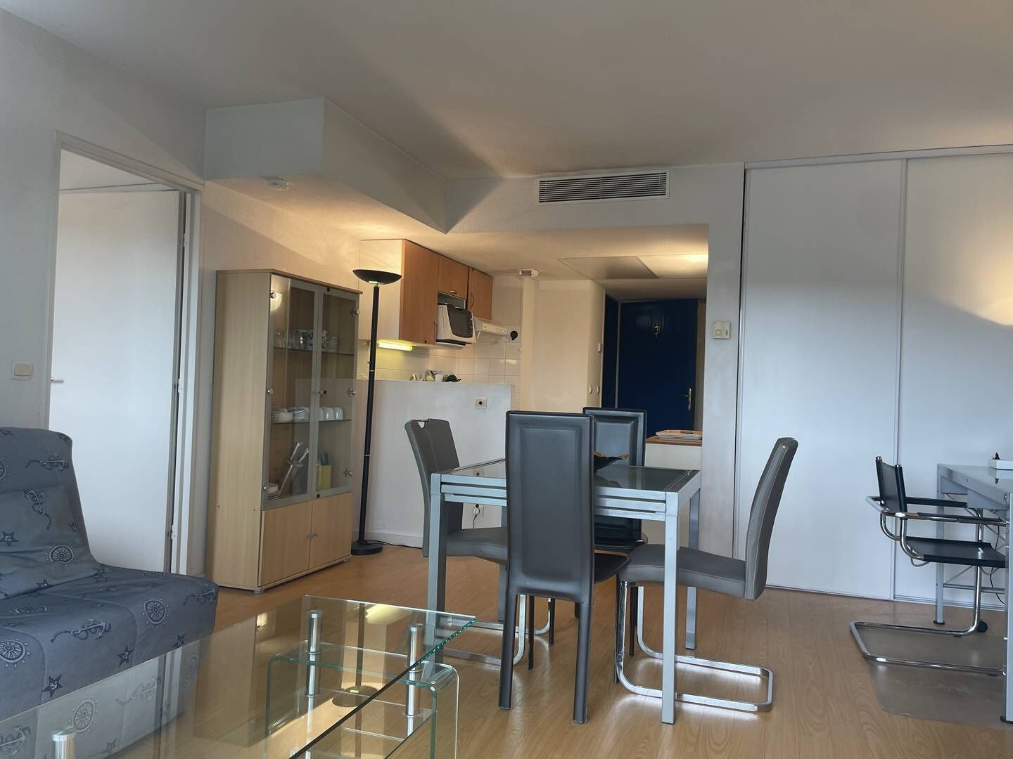 A compact living space with a dining area, kitchenette, and a sofa.
