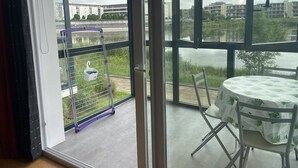 A balcony with a view of a lake, a metal cart, and a table with chairs.