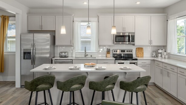 A modern kitchen with white cabinets, stainless steel appliances, and a central island with bar stools. - Brand New 4bd - Modern - Prime Location - Spacious (Raleigh)