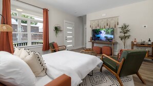 A modern bedroom with a bed, a TV, and a seating area. - Brand New 4bd - Modern - Prime Location - Spacious (Raleigh)