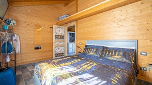 Un dormitorio con paneles de madera, una cama, un armario y un escritorio pequeño.