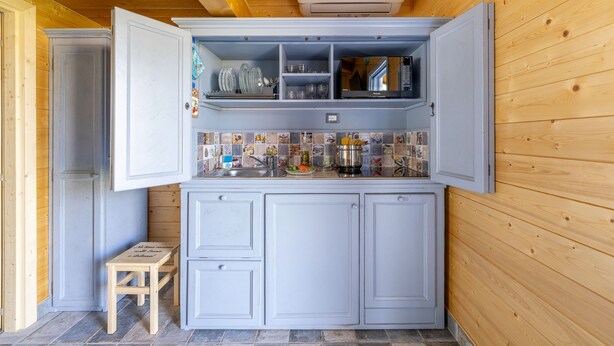 Una cocina con gabinetes blancos, salpicadero de azulejos y techo de madera.