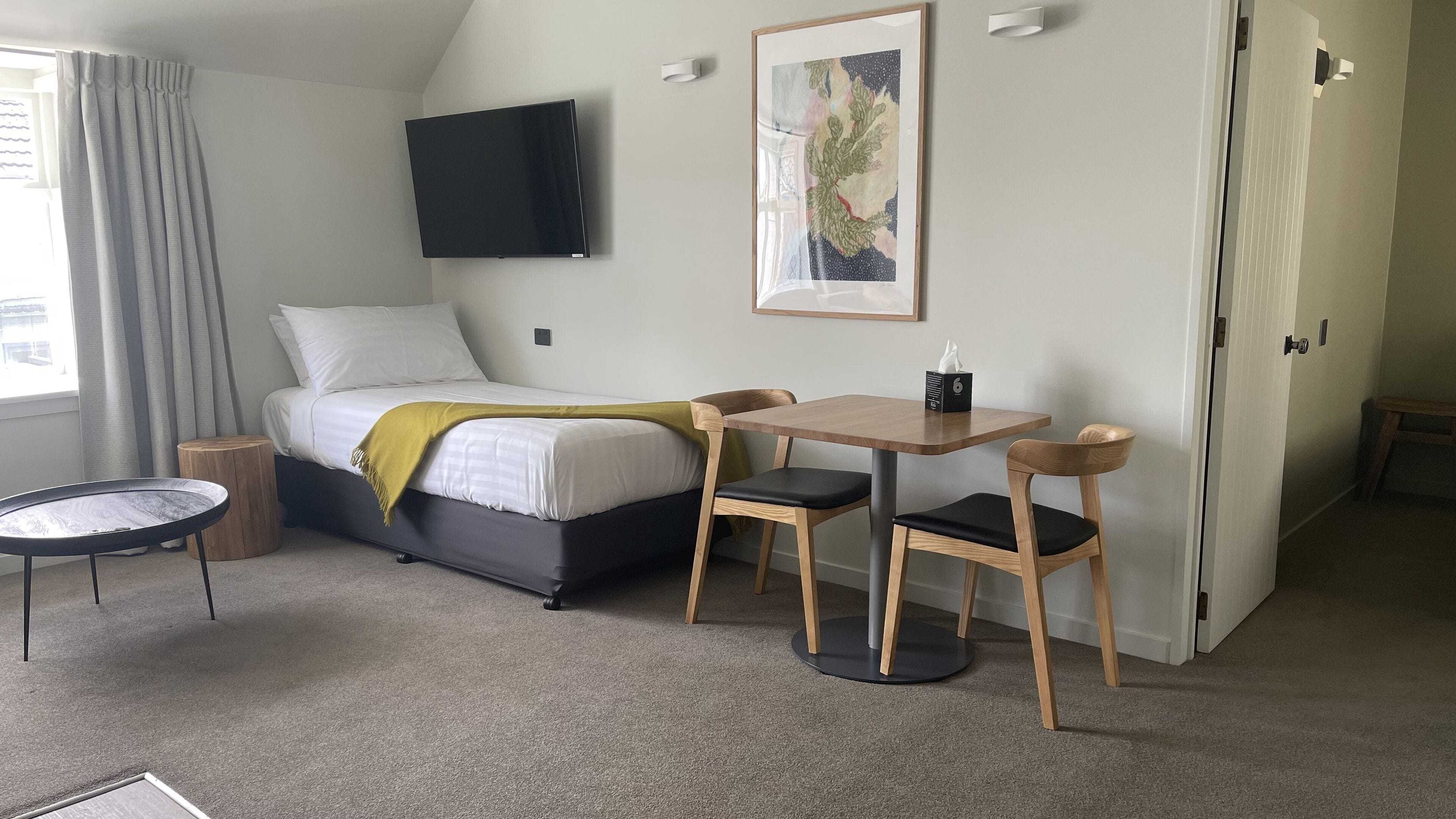 Une chambre à coucher comprenant un lit, une table de chevet, une chaise et une petite table ronde.