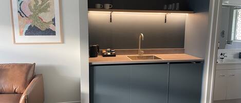 Une cuisine moderne dotée d’un évier encastré, d’une machine à café et d’un plan de travail.