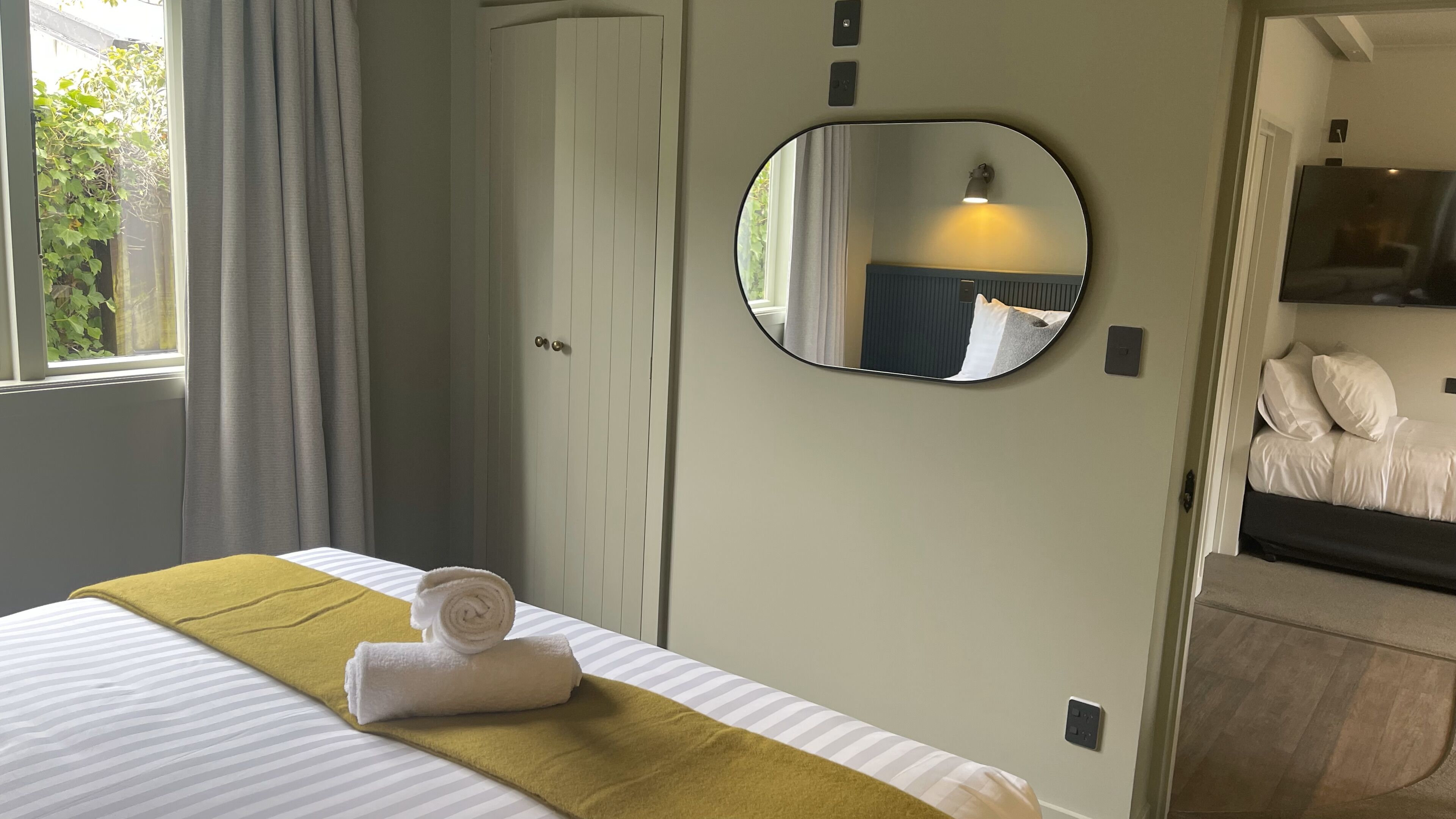 Une chambre d’hôtel avec un lit, un miroir, une armoire et un téléviseur.