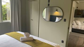 Una habitación de hotel con cama, espejo, armario y televisor.