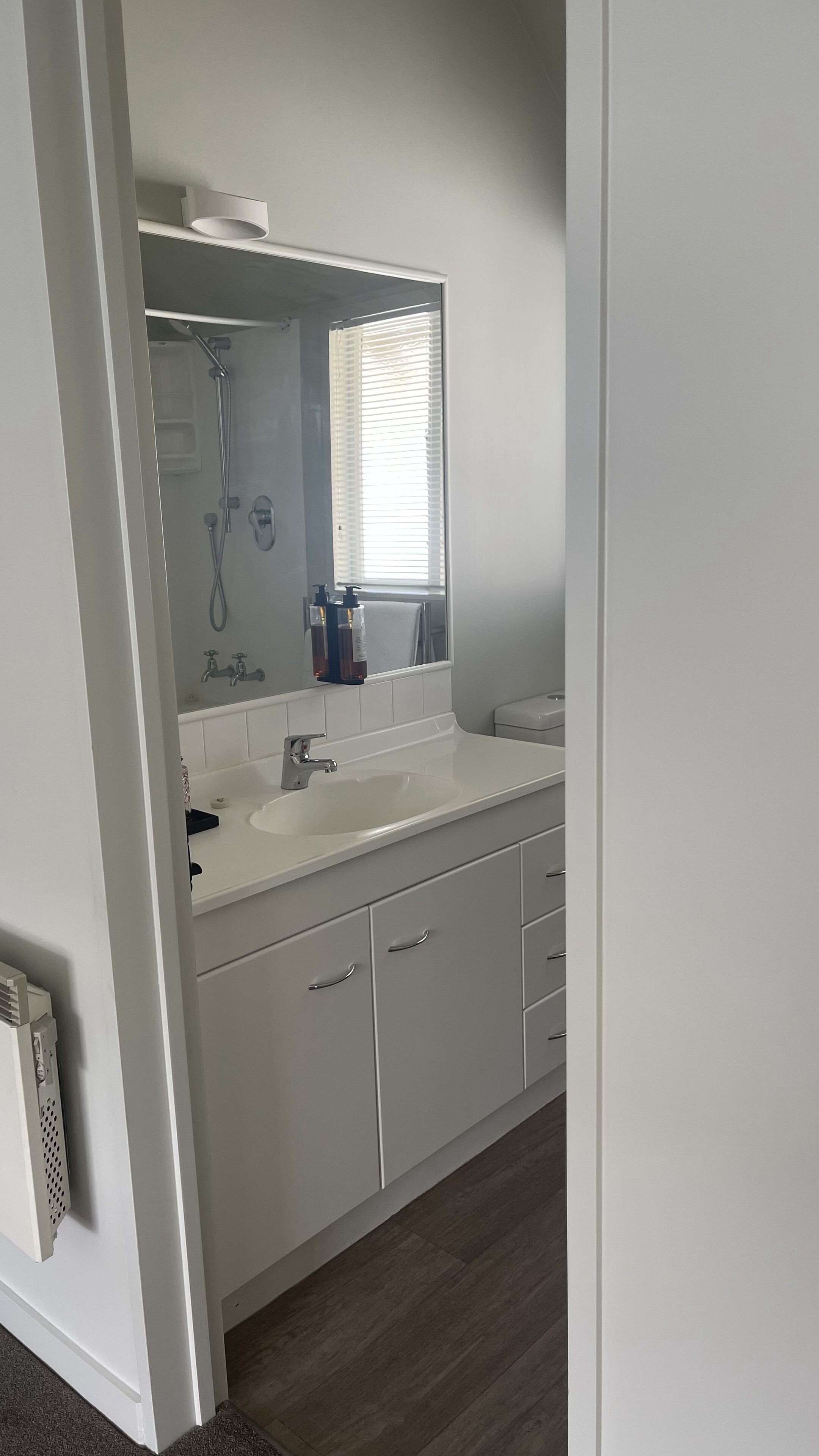A modern bathroom with a white sink, mirror, and shower.