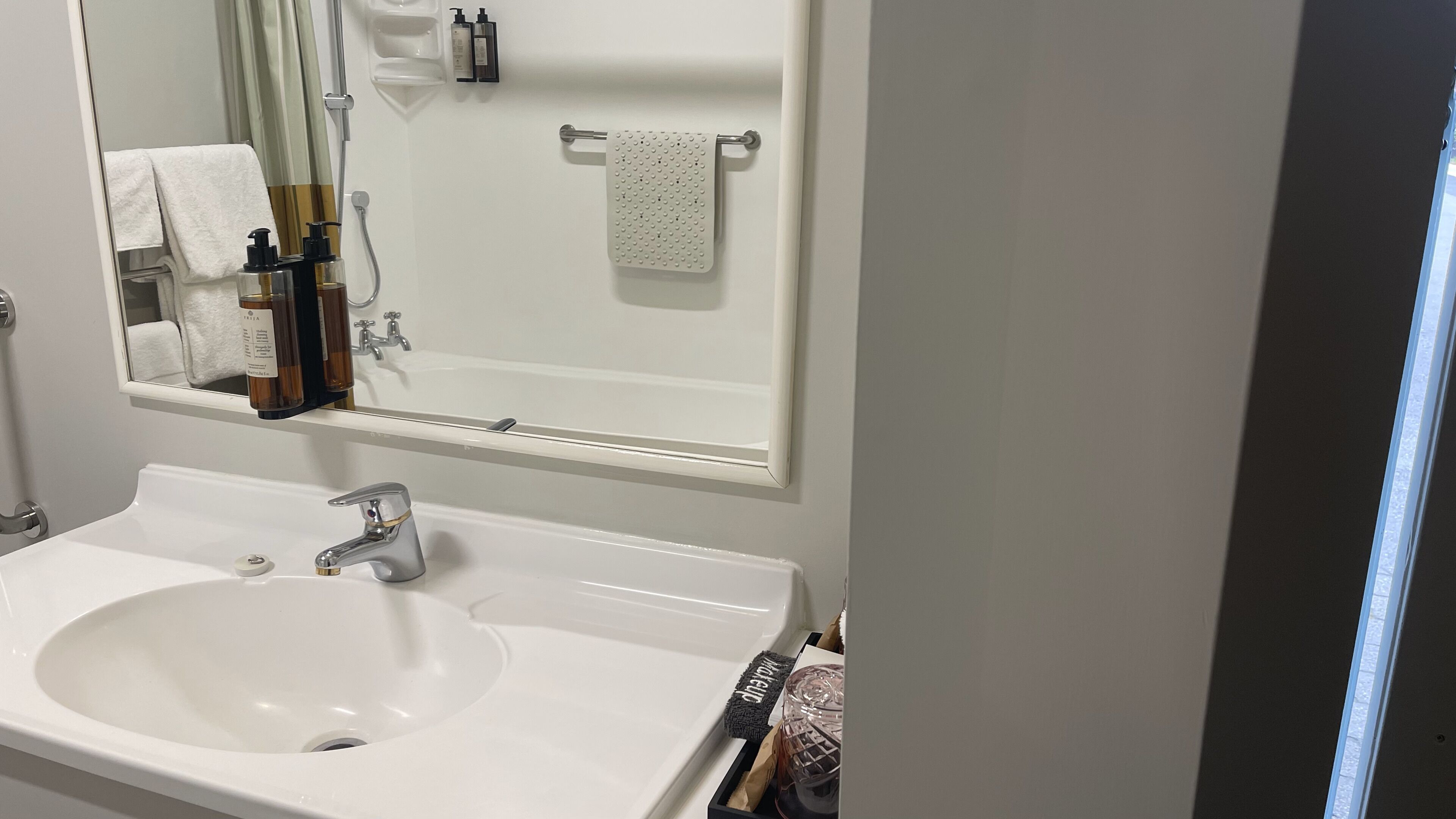 A bathroom with a white sink, a mirror, and a towel rack.