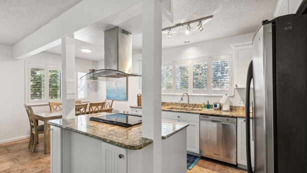 A modern kitchen with white cabinetry, a granite countertop, and stainless steel appliances. - Dogs Welcome! Pool access. 1 Block to beach! Serene retreat under a majestic old oak canopy (Fernandina Beach)