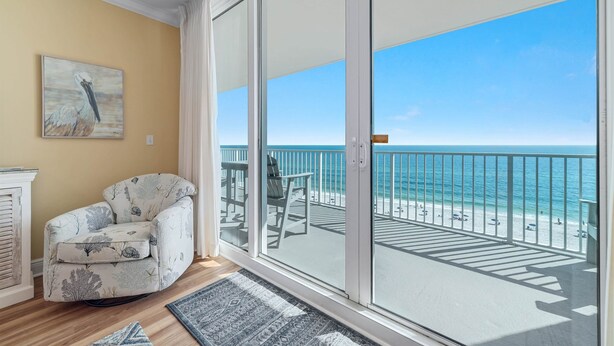 Una habitación con un gran ventanal corredero que da a un balcón con vistas al océano.