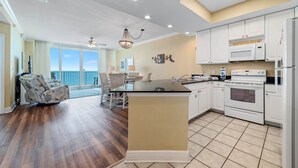Cocina amplia con una isla central, armarios blancos y un ventanal con vistas a un balcón.