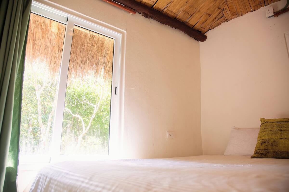 Quarto com cama, janela e teto de madeira.