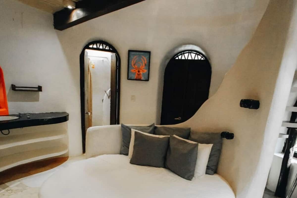 Um quarto espaçoso com uma cama grande, um banco embutido e uma área de banheiro pequena.