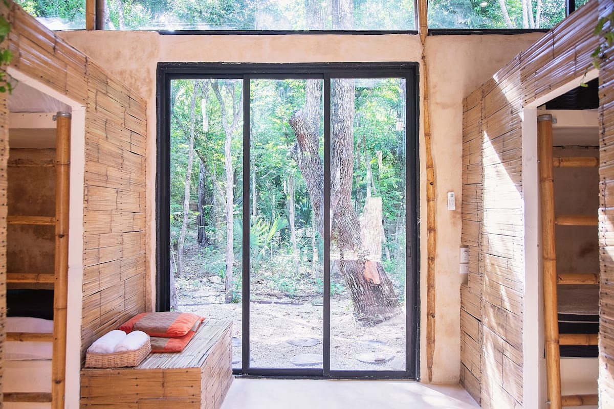 Um quarto de madeira com uma grande porta de correr de vidro que dá para uma área arborizada.