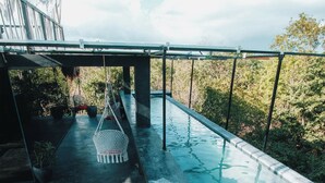 Una piscina en la azotea con vistas a árboles y una estructura de metal.