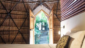 Una habitación con cama, una puerta de madera y vistas a una escalera que da al exterior.