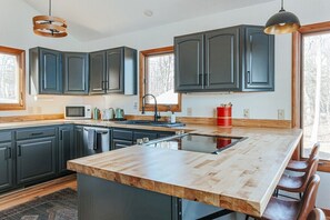A modern kitchen with dark cabinets, a wooden island, and a large window. - Elk Mountain Overlook: Breathtaking Views (Afton)